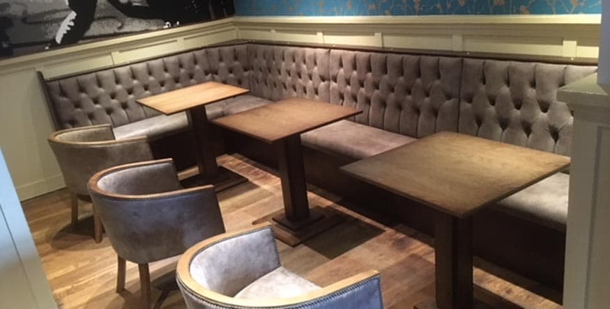 Fixed upholstered banquette seating running along a pub wall